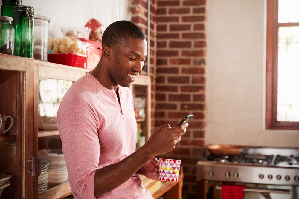 man checking email on phone with coffee in hand