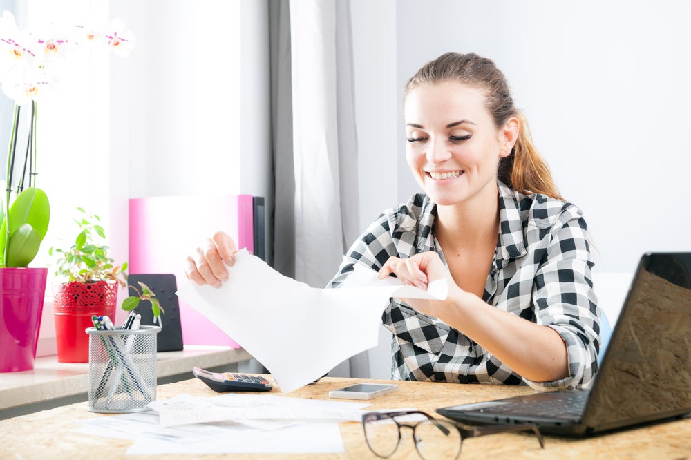 woman smiling while tearing up bill