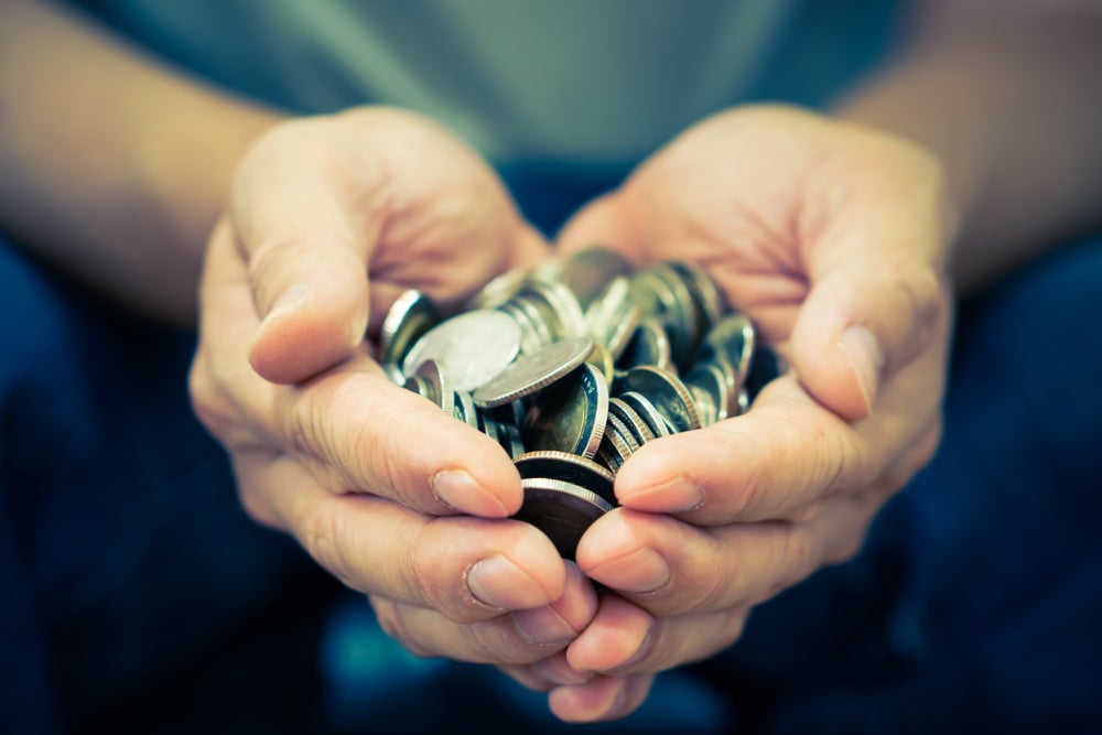 hands in the shape of a heart holding coins