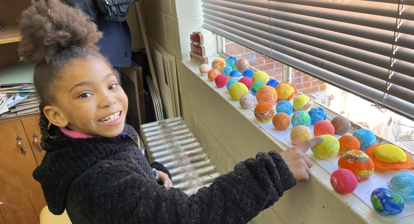 Student with solar system planets made of clay